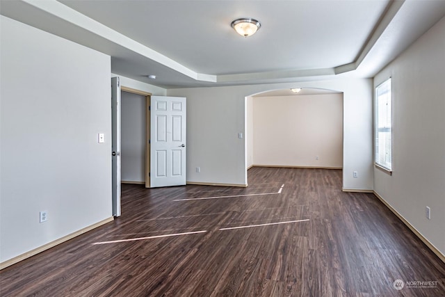 empty room with a tray ceiling and dark hardwood / wood-style floors