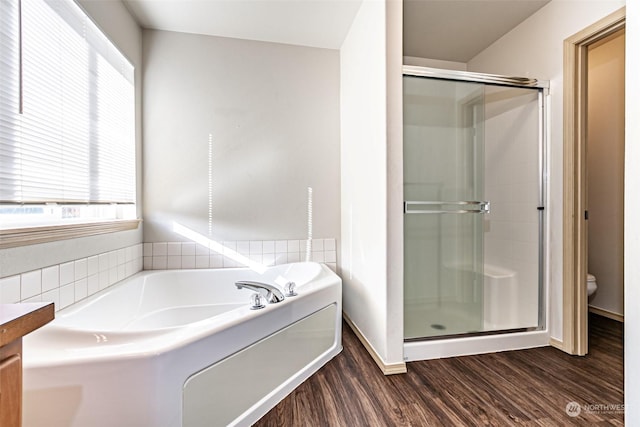 bathroom featuring toilet, hardwood / wood-style floors, and plus walk in shower