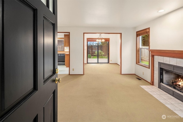 unfurnished living room with light carpet, a notable chandelier, and a fireplace