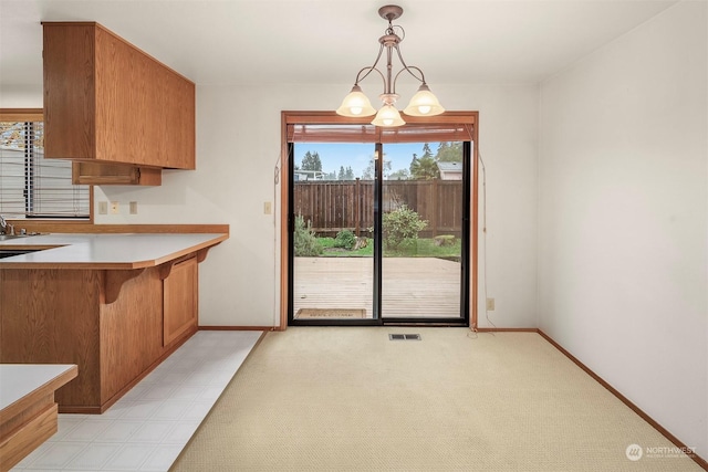 kitchen featuring pendant lighting, light colored carpet, and a chandelier