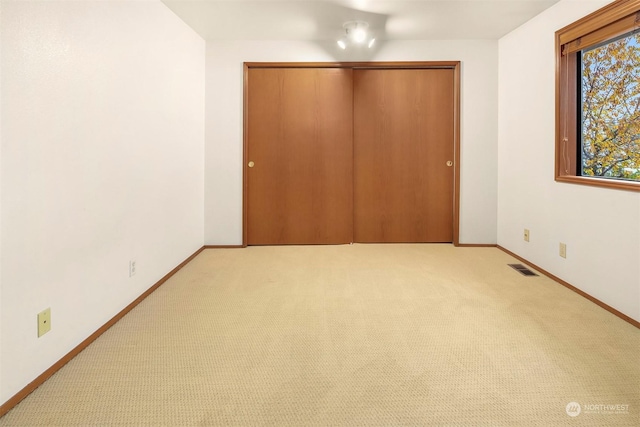 unfurnished bedroom featuring light colored carpet and a closet