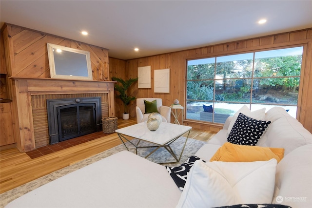 living room with hardwood / wood-style flooring, a brick fireplace, and wood walls