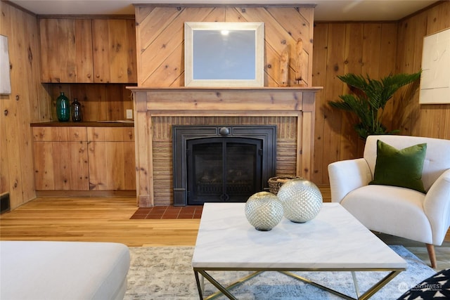 living room featuring a brick fireplace, wooden walls, and light hardwood / wood-style flooring