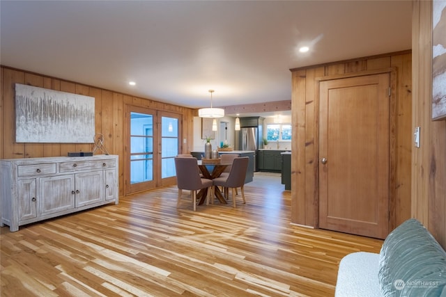 dining room featuring french doors, wooden walls, and light wood-type flooring