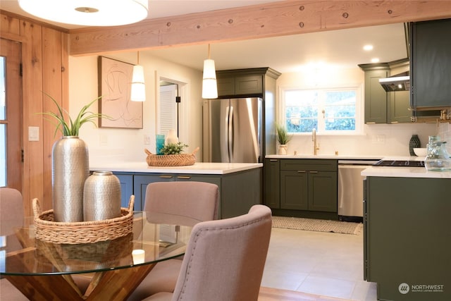 kitchen with sink, tasteful backsplash, hanging light fixtures, appliances with stainless steel finishes, and wall chimney range hood