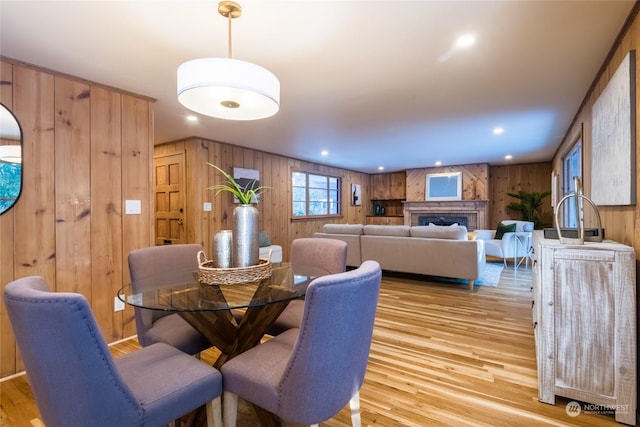 dining space with wooden walls and light wood-type flooring