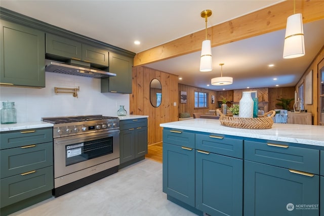 kitchen featuring hanging light fixtures, stainless steel gas range oven, beam ceiling, and wood walls