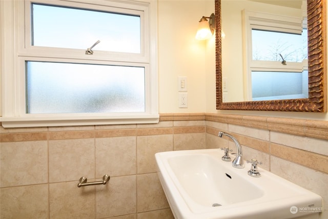 bathroom with sink, a wealth of natural light, and tile walls