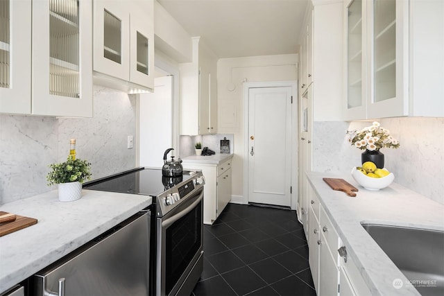 kitchen featuring white cabinetry, stainless steel electric range oven, dark tile patterned flooring, light stone countertops, and decorative backsplash