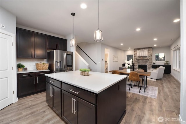 kitchen with a kitchen island, pendant lighting, tasteful backsplash, stainless steel fridge with ice dispenser, and light hardwood / wood-style flooring