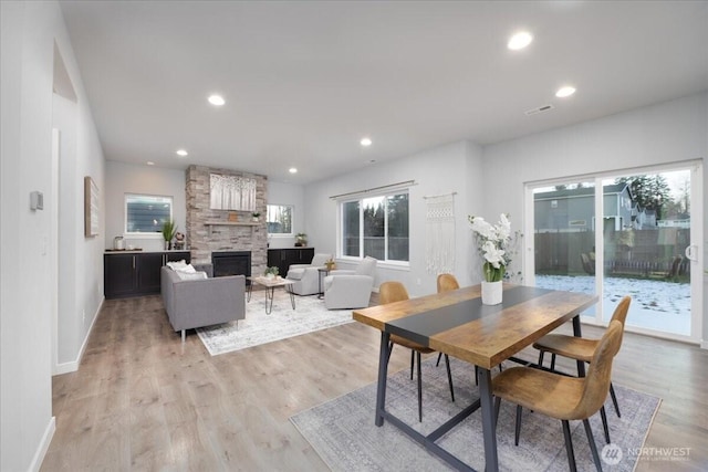 dining space featuring a stone fireplace and light hardwood / wood-style floors