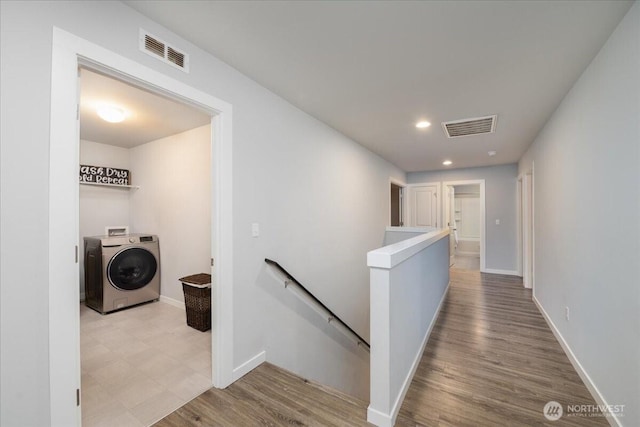 hallway with washer / clothes dryer and light hardwood / wood-style flooring