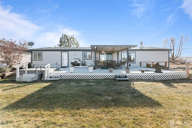 rear view of property featuring a wooden deck and a lawn