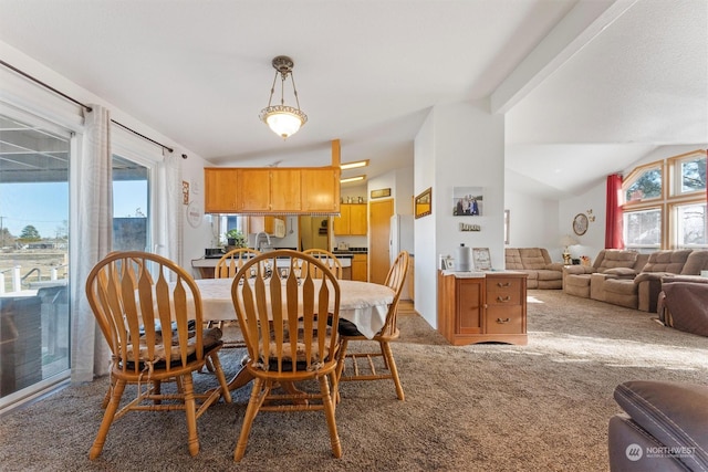 carpeted dining space with vaulted ceiling