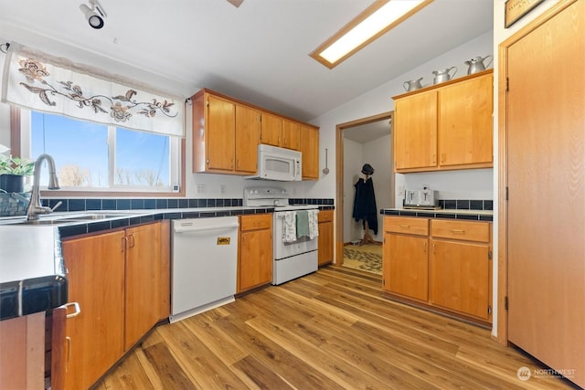 kitchen featuring lofted ceiling, sink, white appliances, and tile counters