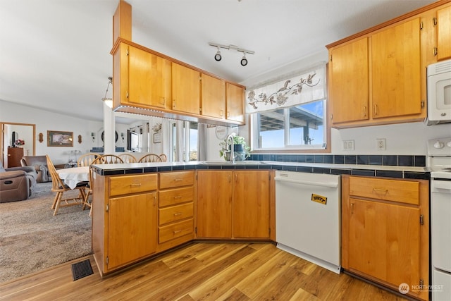 kitchen featuring sink, light wood-type flooring, tile counters, kitchen peninsula, and white appliances