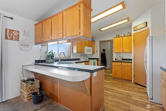 kitchen with lofted ceiling, sink, light hardwood / wood-style flooring, kitchen peninsula, and white appliances