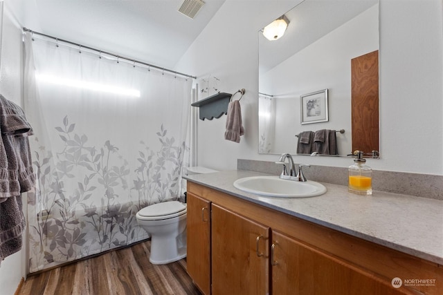 full bathroom with vaulted ceiling, hardwood / wood-style flooring, vanity, shower / tub combo, and toilet