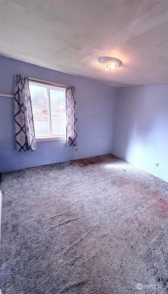 unfurnished room featuring carpet flooring and a textured ceiling