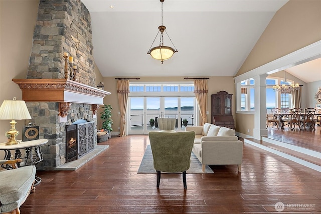 living area with hardwood / wood-style floors, baseboards, ornate columns, high vaulted ceiling, and a fireplace