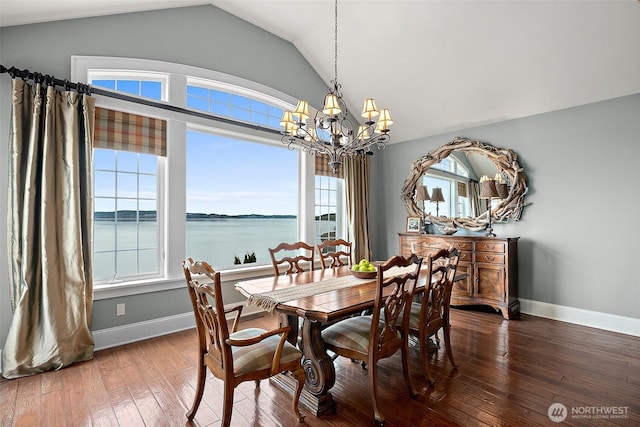 dining room featuring baseboards, a water view, vaulted ceiling, an inviting chandelier, and wood-type flooring