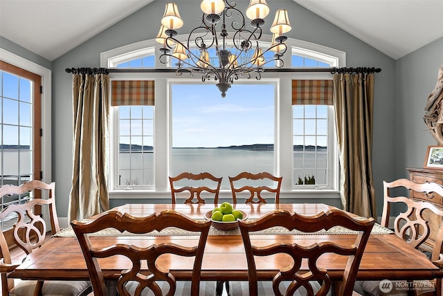 dining room featuring a wealth of natural light, lofted ceiling, an inviting chandelier, and a water view