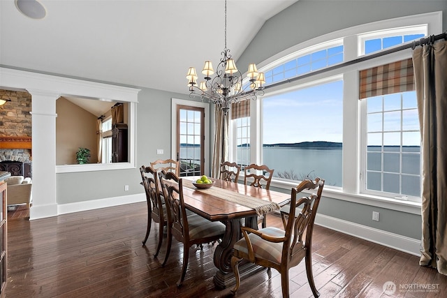 dining room with dark wood-style floors, a fireplace, baseboards, a chandelier, and vaulted ceiling