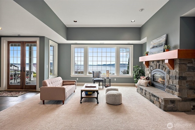 living area with recessed lighting, french doors, carpet floors, a stone fireplace, and baseboards