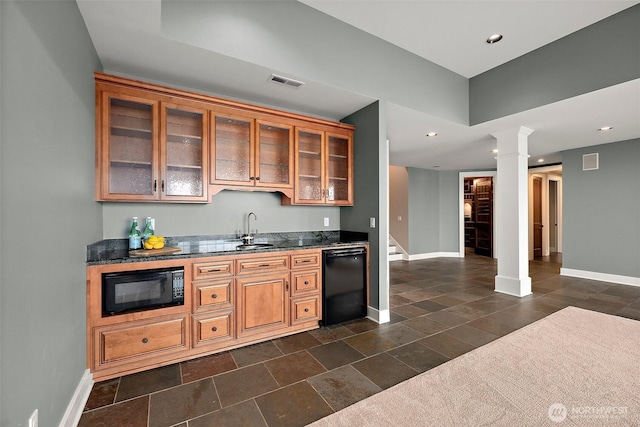 kitchen featuring glass insert cabinets, baseboards, black appliances, ornate columns, and a sink