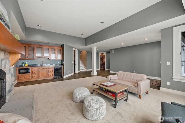 carpeted living area featuring a sink, wet bar, baseboards, stairs, and ornate columns