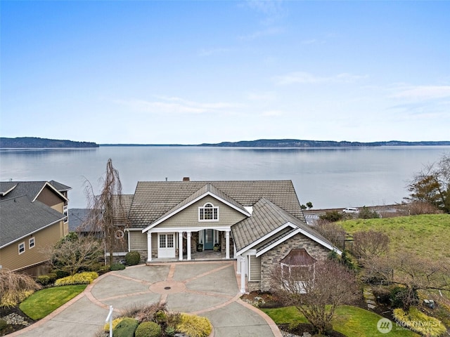 view of front of house with stone siding, a tile roof, and a water view