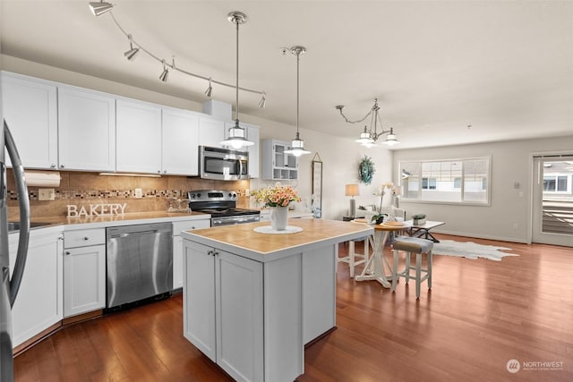 kitchen featuring pendant lighting, white cabinetry, stainless steel appliances, a kitchen island, and decorative backsplash