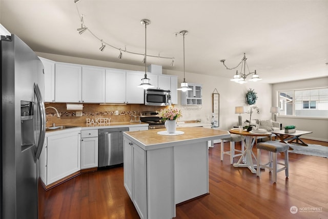 kitchen with white cabinetry, sink, stainless steel appliances, and a kitchen island