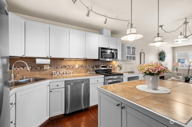 kitchen with stainless steel appliances, white cabinets, and decorative light fixtures