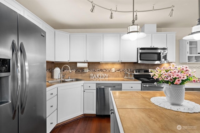 kitchen with sink, appliances with stainless steel finishes, backsplash, white cabinets, and decorative light fixtures