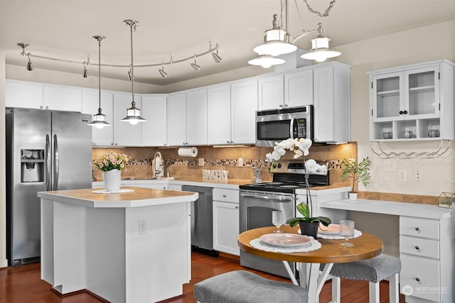 kitchen featuring decorative light fixtures, white cabinetry, sink, a center island, and stainless steel appliances