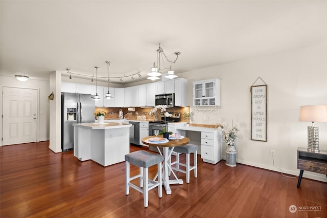 kitchen with a breakfast bar area, appliances with stainless steel finishes, white cabinetry, a kitchen island, and decorative light fixtures