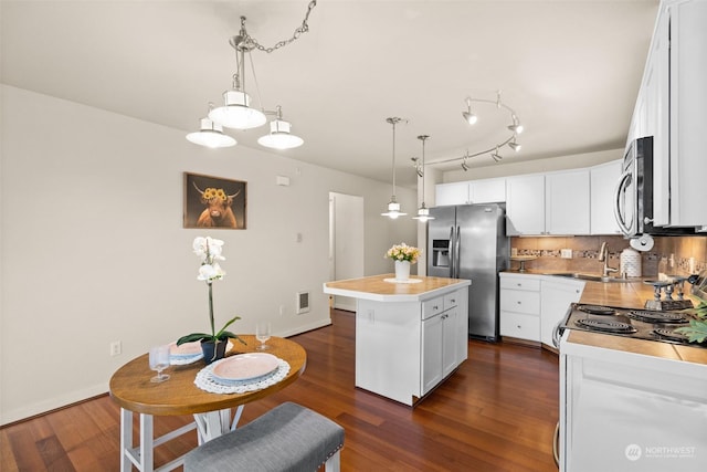 kitchen with a center island, dark hardwood / wood-style flooring, white cabinets, stainless steel appliances, and backsplash