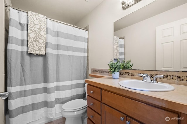 bathroom with vanity, decorative backsplash, and toilet