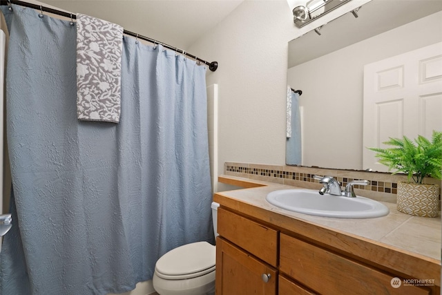 bathroom with vanity, decorative backsplash, and toilet