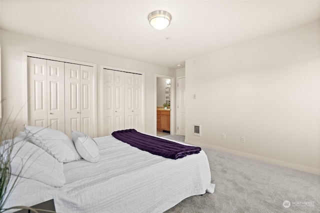 bedroom featuring multiple closets and carpet floors