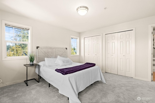 bedroom with light carpet and two closets