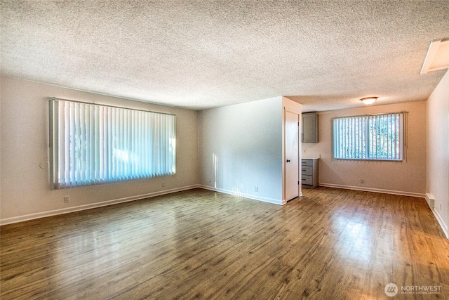 unfurnished room featuring a textured ceiling, wood finished floors, and baseboards