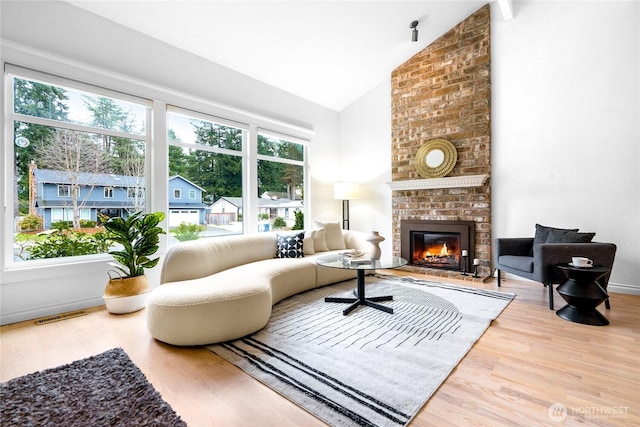 living room with hardwood / wood-style flooring, high vaulted ceiling, a wealth of natural light, and a fireplace