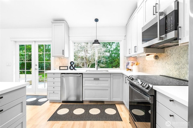 kitchen with light hardwood / wood-style flooring, backsplash, pendant lighting, stainless steel appliances, and white cabinets