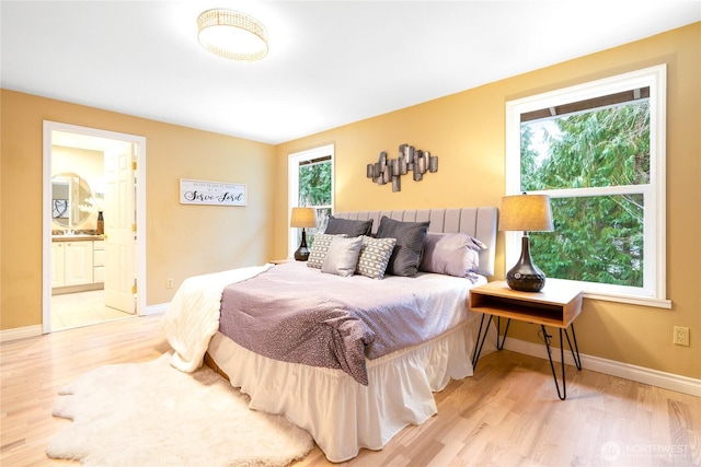 bedroom with light wood-type flooring and ensuite bathroom