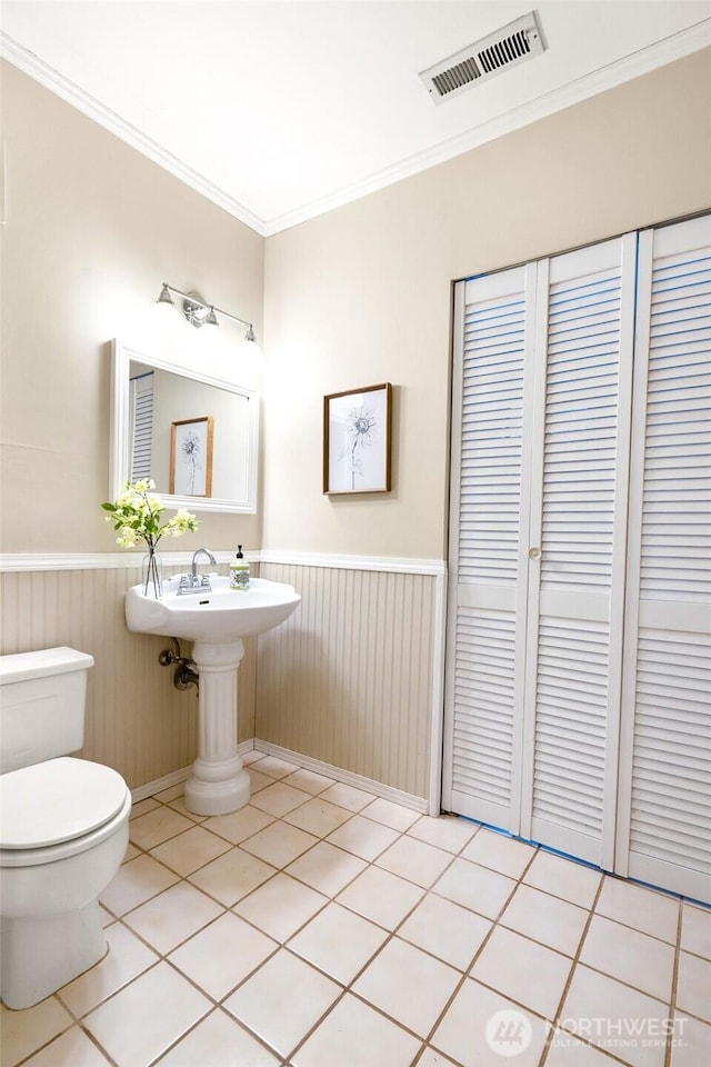 bathroom featuring tile patterned flooring, toilet, and ornamental molding