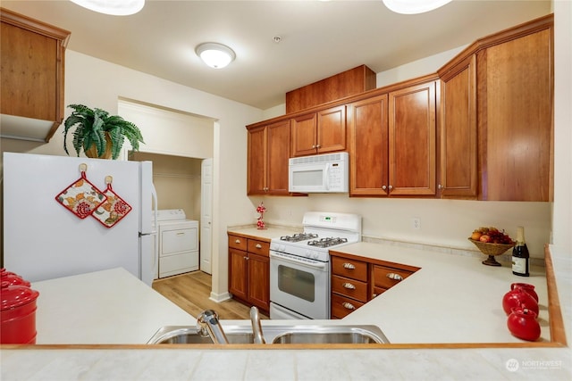 kitchen featuring sink, washing machine and clothes dryer, white appliances, and light hardwood / wood-style flooring