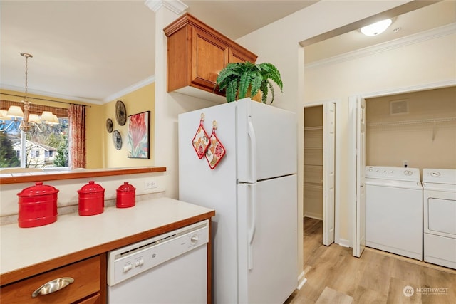 kitchen with ornamental molding, washer and clothes dryer, white appliances, and decorative light fixtures