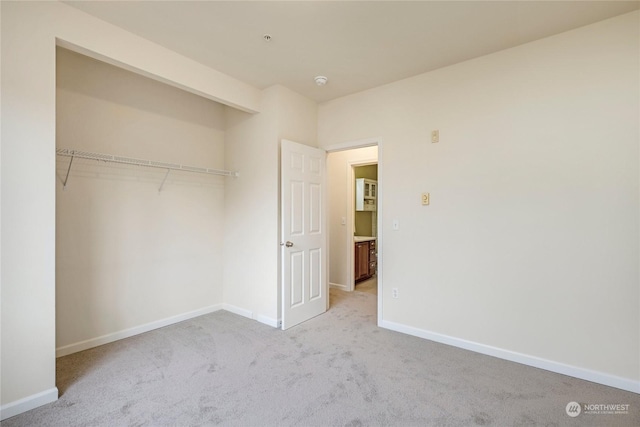 unfurnished bedroom featuring light colored carpet and a closet